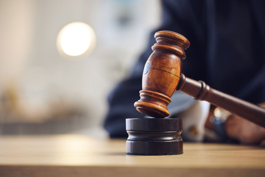 A wooden gavel rests on a black block, likely used to call a meeting to order.