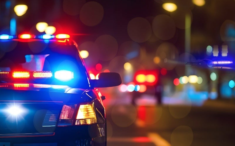 Police car with its emergency lights on, parked on a city street at night