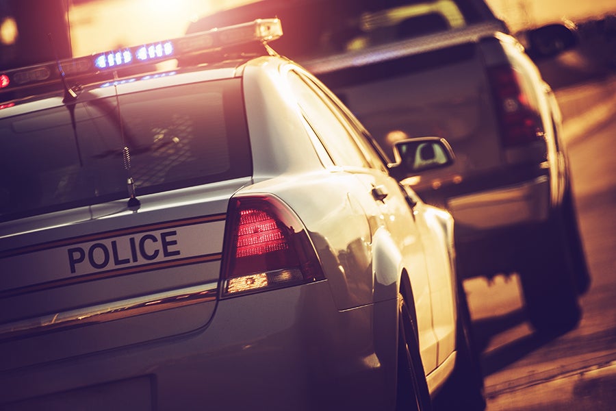 A police car with flashing lights drives down a dark road.